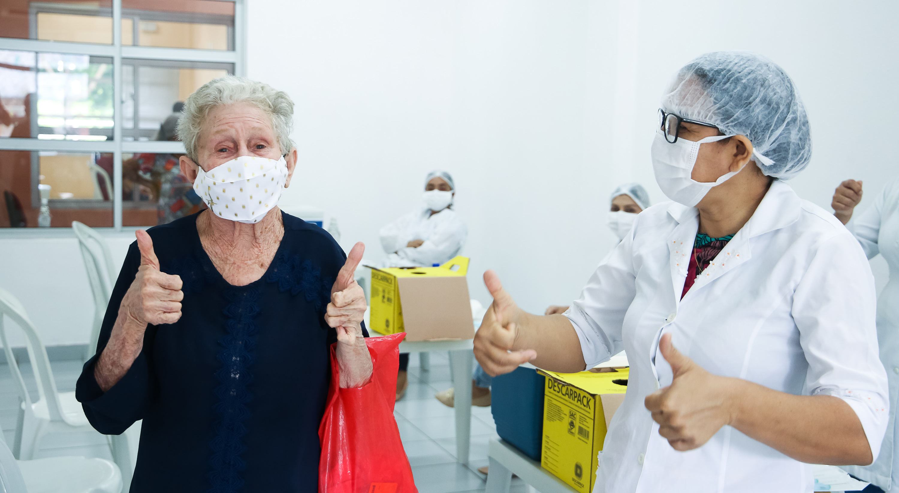 senhora e enfermeira fazerm sinal de positivo para a câmera